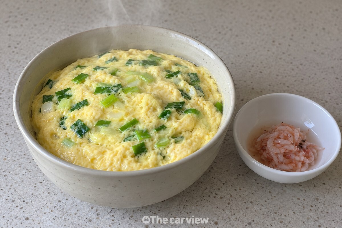 김이 은은히 오르는 계란찜 곁에 새우젓을 조금 올려 둔 모습. / 기사 이해를 돕기 위한 생성형 이미지