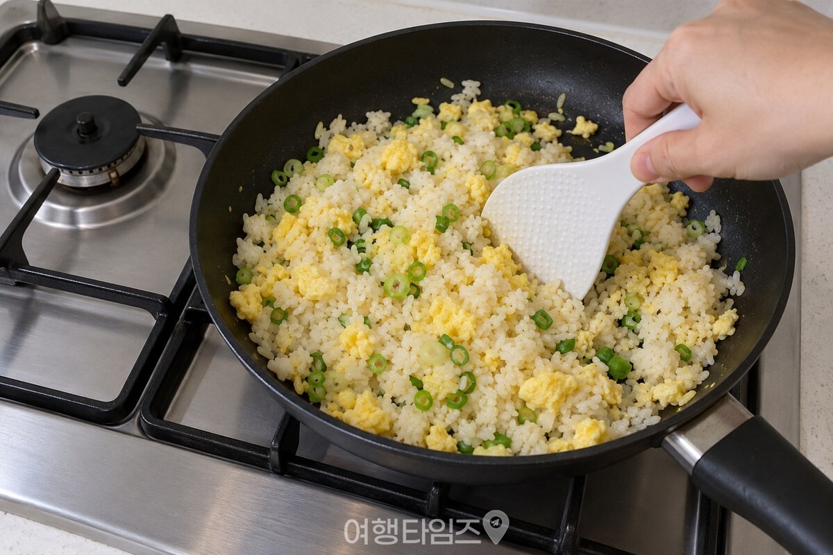 불을 끈 팬에서 주걱으로 밥알을 푸는 모습 / 기사 이해를 돕기 위한 생성형 이미지