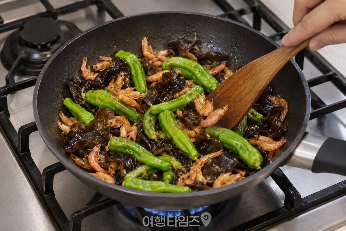 꽈리고추와 목이버섯, 건새우를 팬에서 섞어 볶는 모습 / 기사 이해를 돕기 위한 생성형 이미지