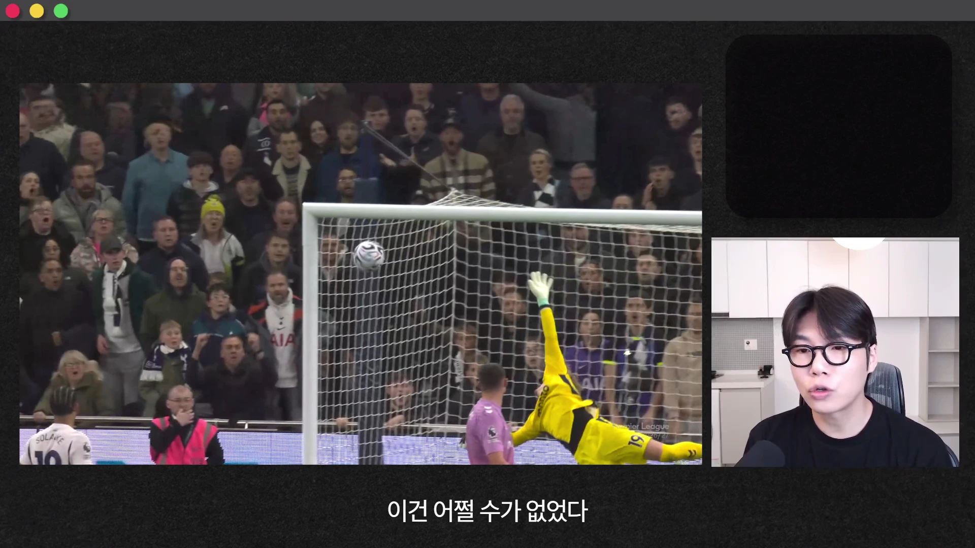 축구 경기장에서 골문으로 빨려 들어가는 공을 막지 못하고 몸을 날리는 골키퍼의 모습이 왼쪽 화면에 나오고, 오른쪽에는 검은색 티셔츠를 입고 안경을 쓴 남성이 마이크 앞에서 이야기하는 모습이 담긴 화면.