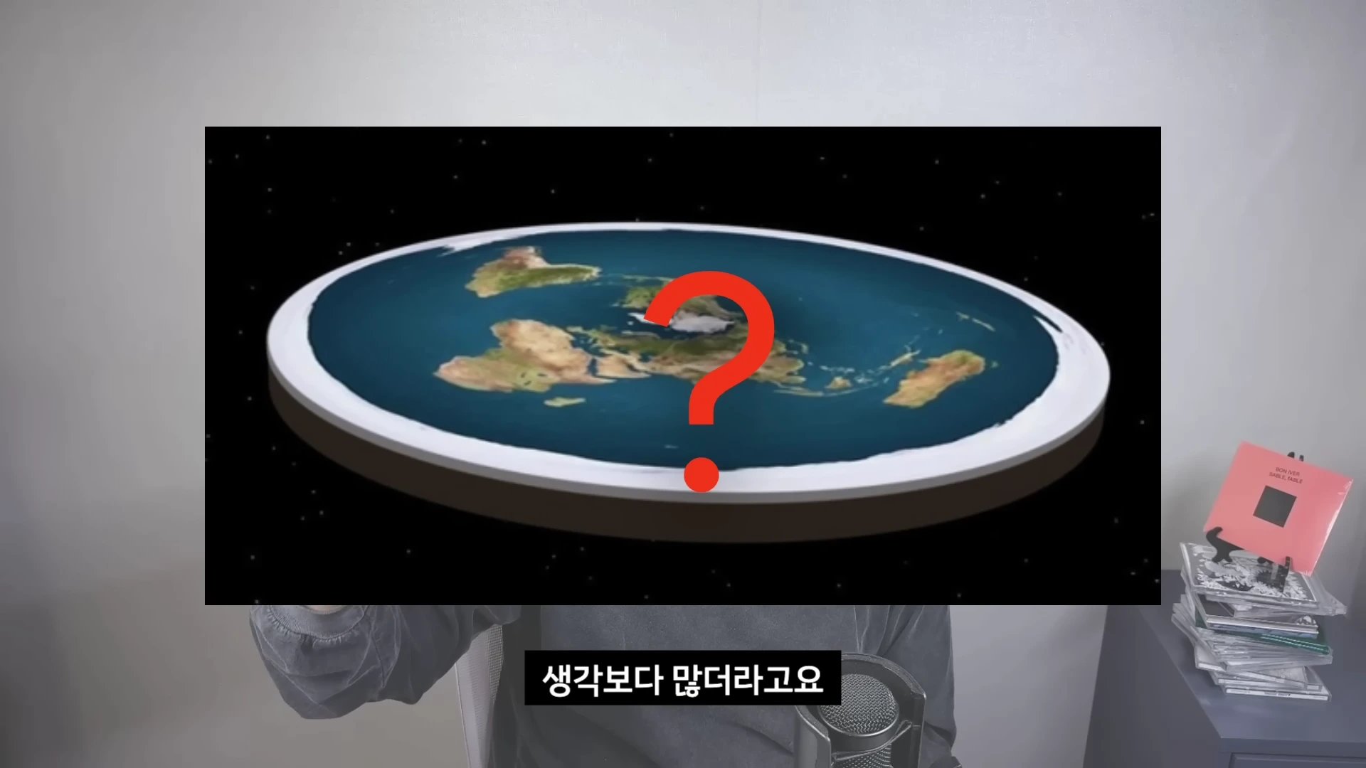 화면 중앙에 평평한 지구 모양의 일러스트와 그 위에 빨간색 물음표가 크게 그려져 있는 영상 프레임