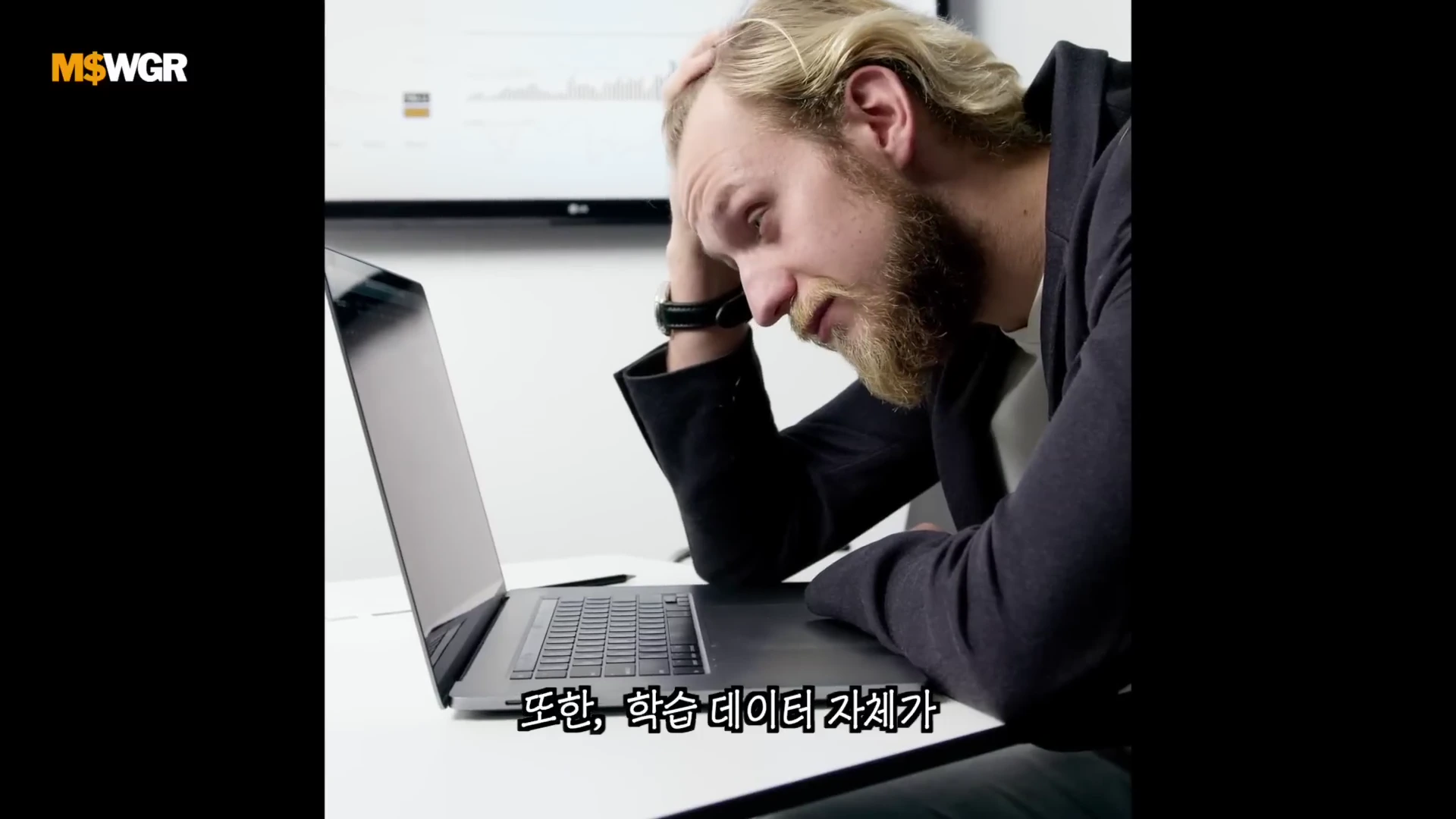 노트북 앞에 앉아 머리를 짚으며 고민하는 표정의 금발 남성