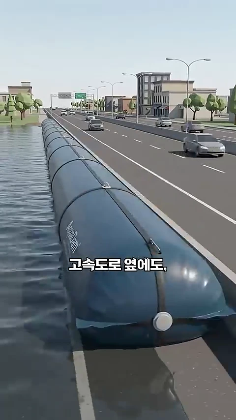 도로 옆에 길게 설치된 원통형의 푸른색 아쿠아댐이 홍수를 막고 있는 그래픽 영상.