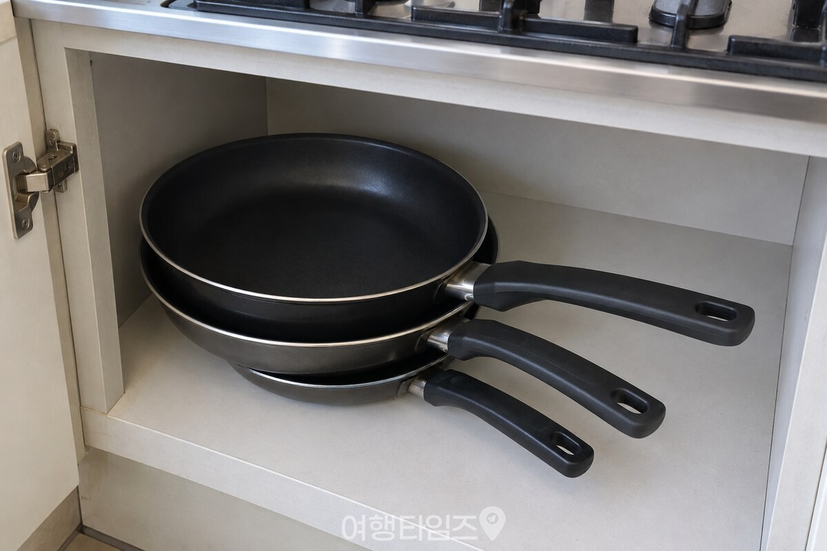 하부장 안에서 크기가 다른 프라이팬이 포개져 손잡이가 엇갈린 상태. / 기사 이해를 돕기 위한 생성형 이미지