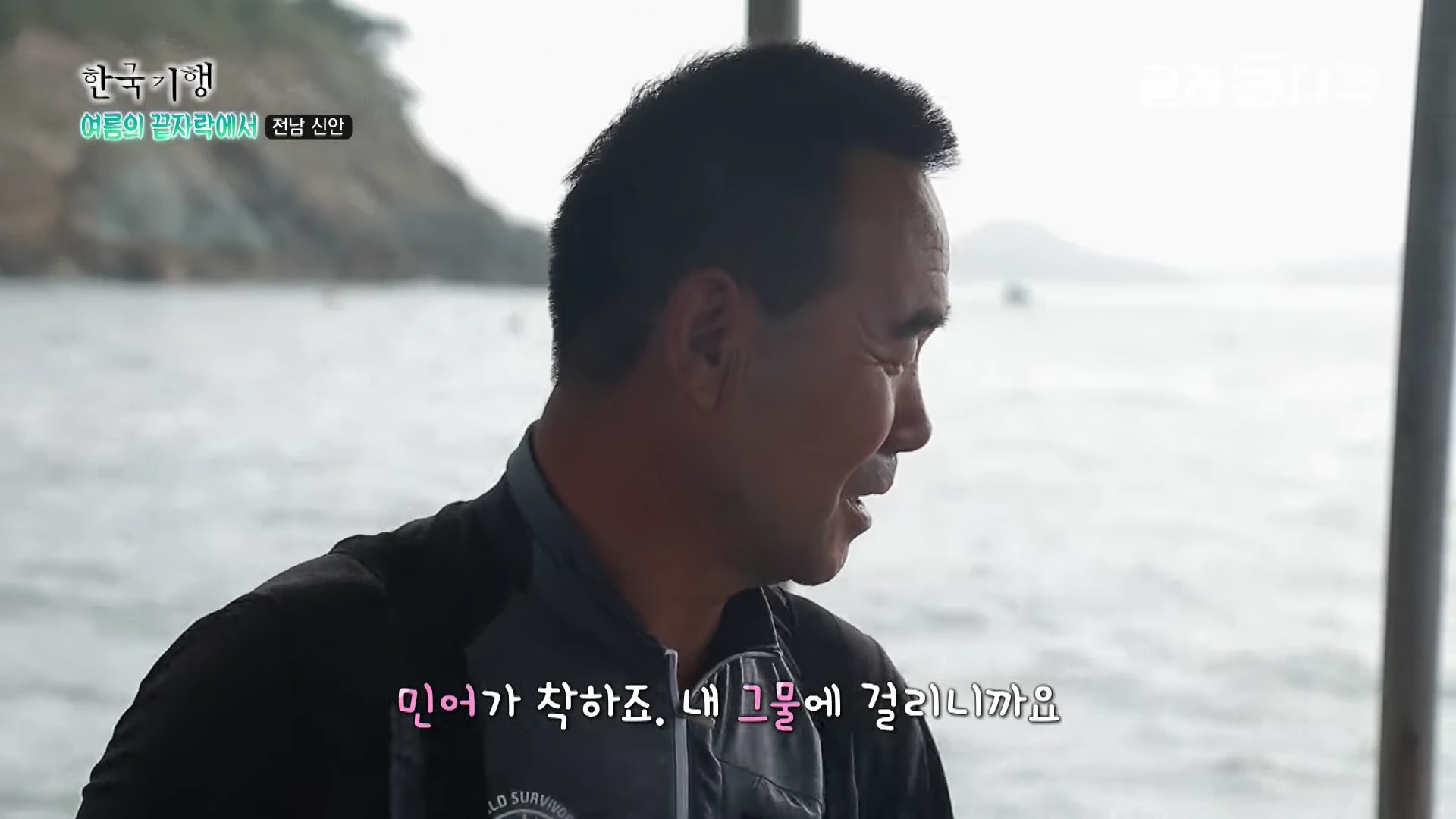 배 위에서 바다를 바라보며 웃고 있는 남성의 옆모습과 '민어가 착하죠. 내 그물에 걸리니까요'라는 자막이 화면 하단에 표시되어 있다.