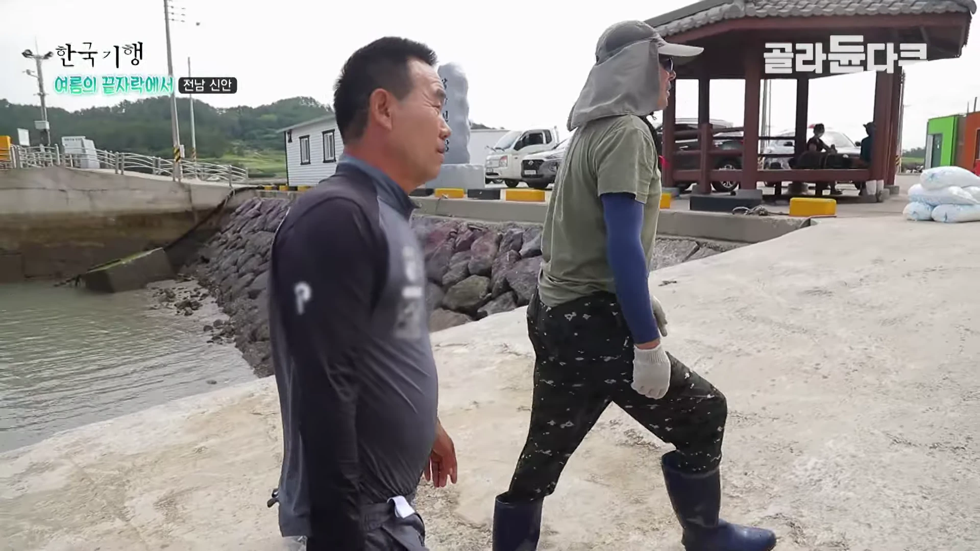 두 남자가 전라남도 신안의 선착장 부두를 함께 걷고 있는 모습