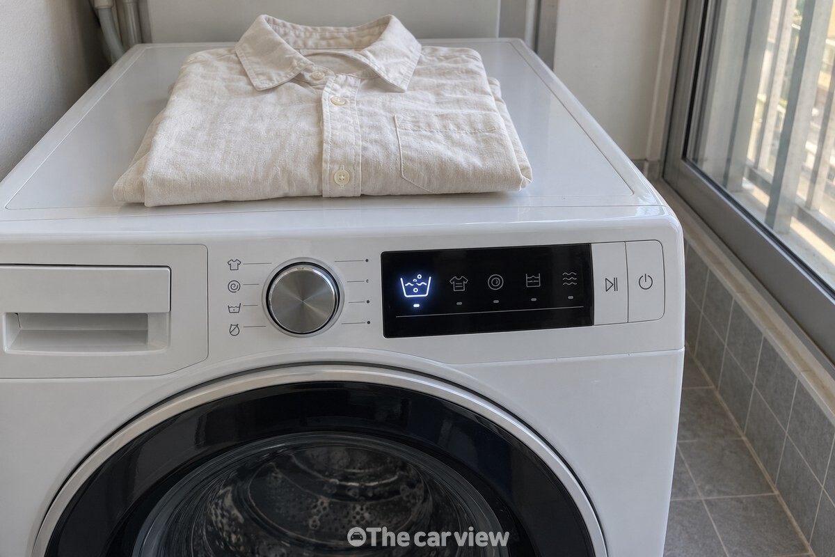 불림 기능을 선택한 드럼세탁기 앞의 긴소매 옷 / 기사 이해를 돕기 위한 생성형 이미지