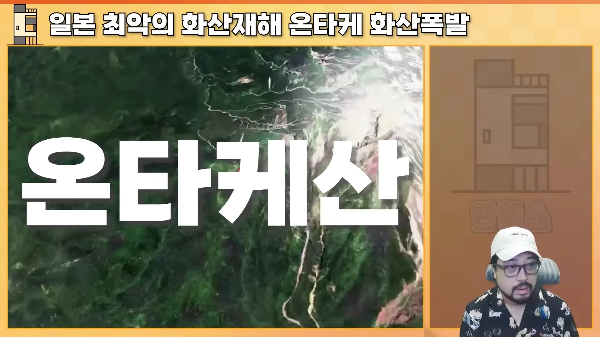 안경을 쓴 남성이 오른쪽에 앉아 있고 왼쪽에는 온타케산의 위성 사진과 함께 '온타케산'이라는 큰 자막이 화면에 배치되어 있다.