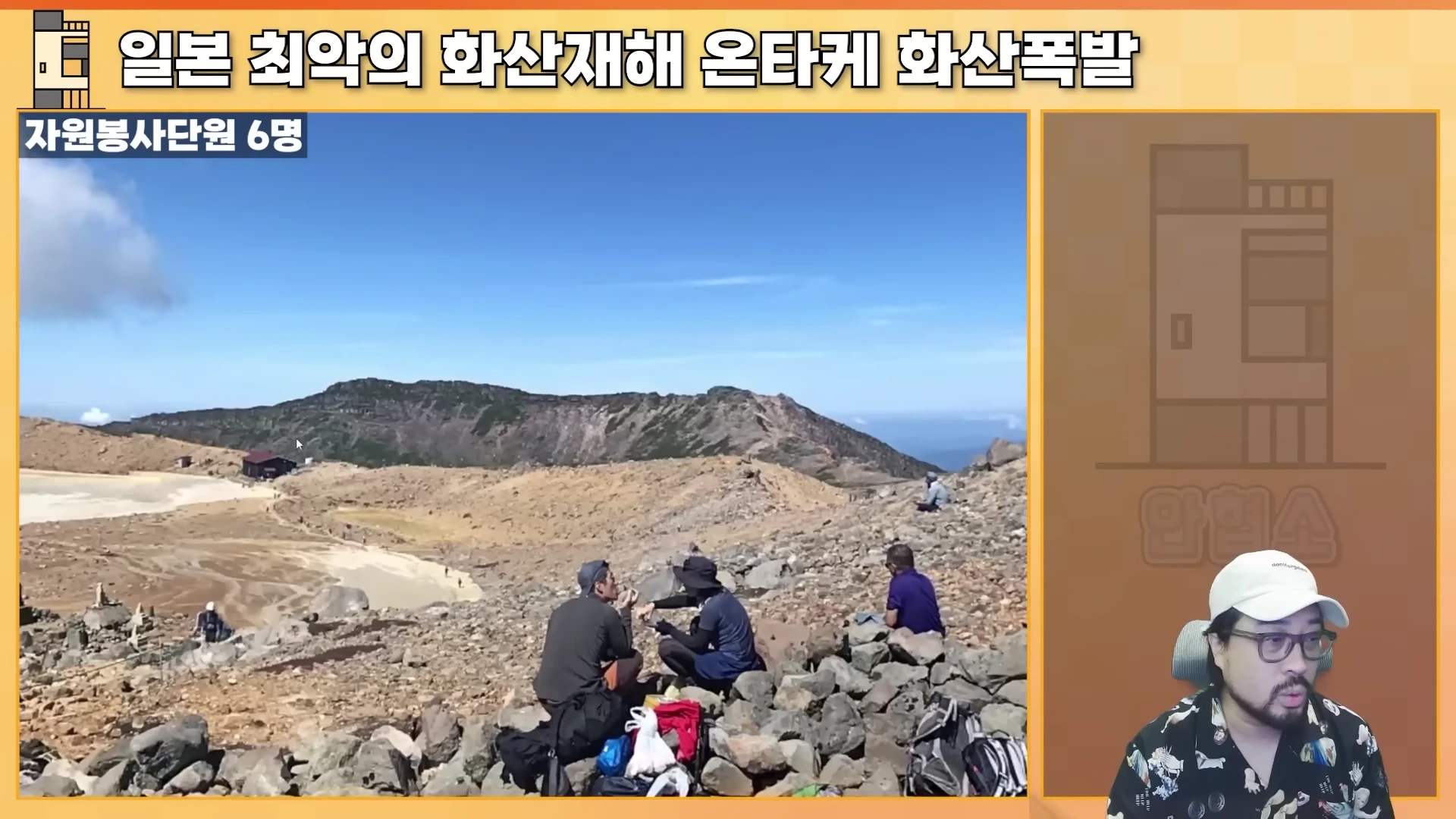 맑은 날씨의 온타케산 정상 풍경을 담은 영상과 이를 설명하는 남성 출연자의 모습이 분할 화면으로 구성된 유튜브 영상 캡처 화면입니다.
