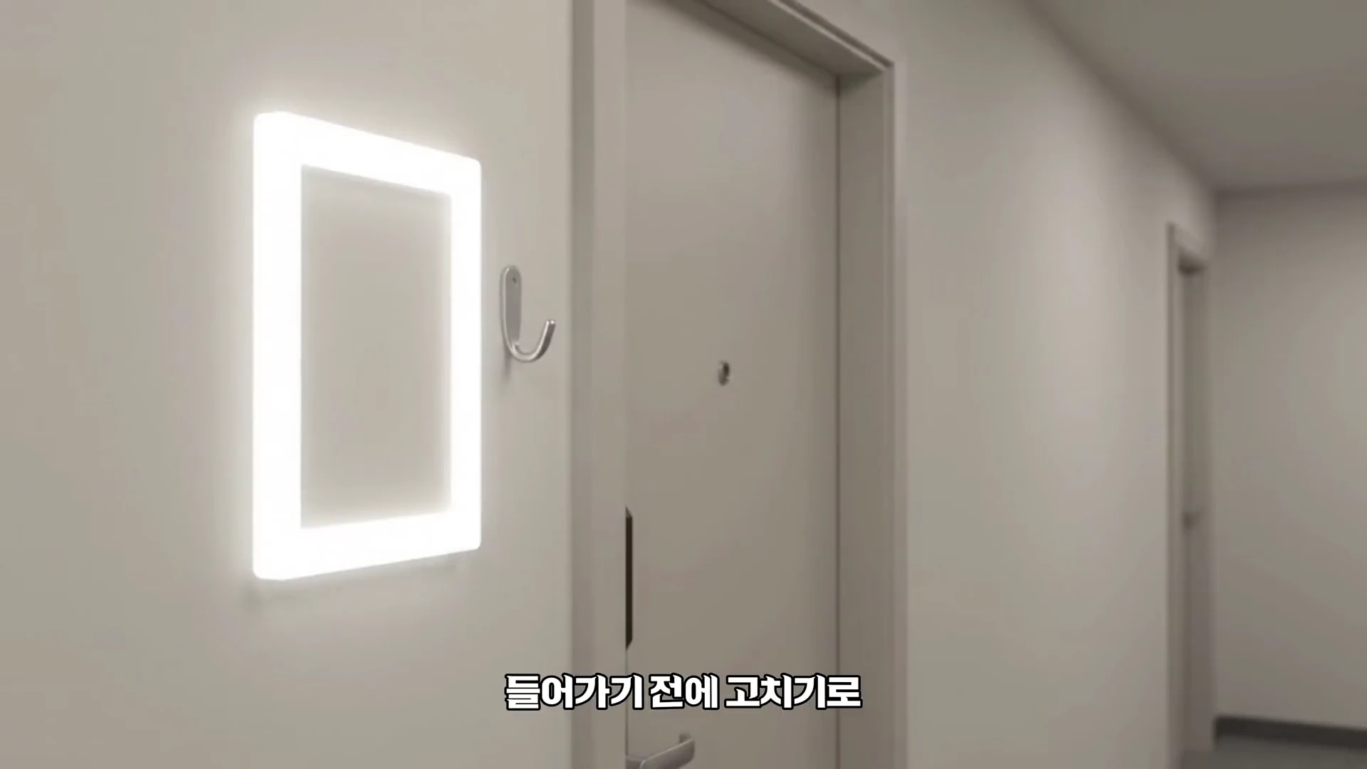 깔끔한 복도의 아파트 현관문 옆에 직사각형의 LED 조명이 켜져 있고, 그 아래 '들어가기 전에 고치기로'라는 자막이 적힌 영상 화면.