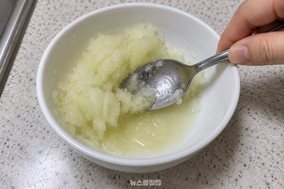 작은 흰 그릇에 간 양파와 맑은 양파즙을 숟가락으로 누르는 모습 / 기사 이해를 돕기 위한 생성형 이미지