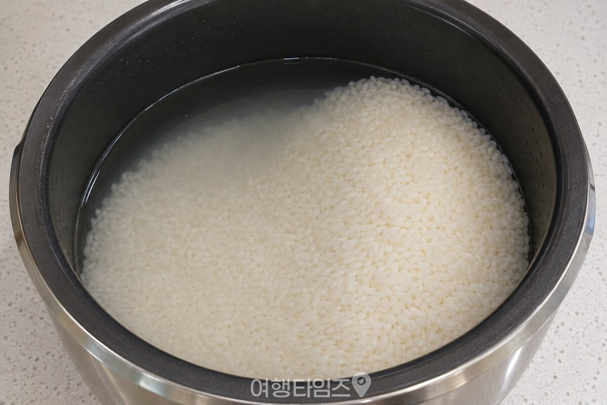내솥 한쪽에 높게 쌓고 반대쪽에 낮게 펼친 물 맞춘 쌀 / 기사 이해를 돕기 위한 생성형 이미지