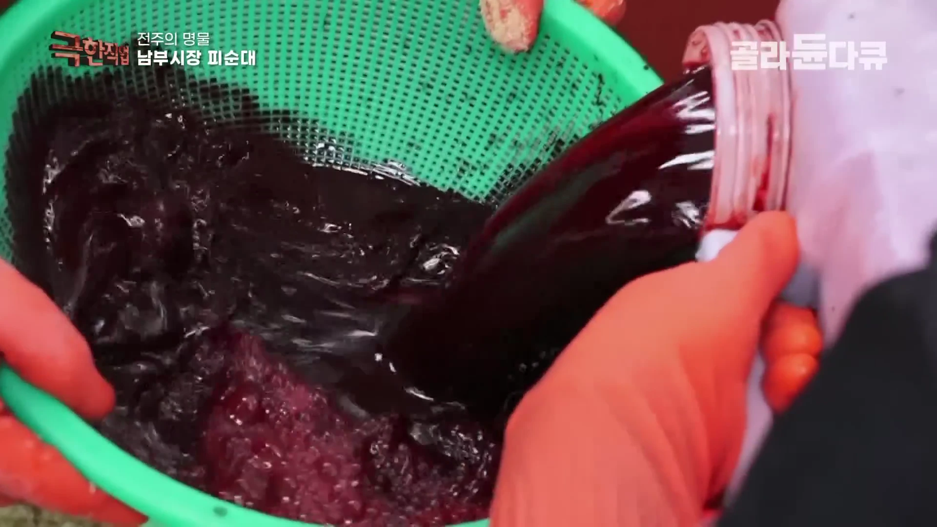 주황색 고무장갑을 낀 사람이 녹색 소쿠리에 담긴 재료 위로 붉은빛이 도는 검은색 선지를 붓고 있는 모습