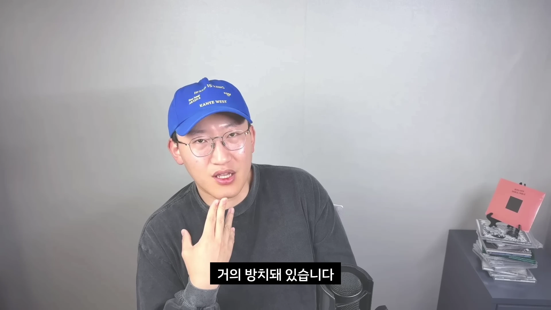 파란색 야구 모자와 안경을 착용한 남성이 회색 배경 앞에서 마이크를 앞에 두고 이야기를 나누고 있다. 하단에는 '거의 방치돼 있습니다'라는 자막이 표시되어 있다.