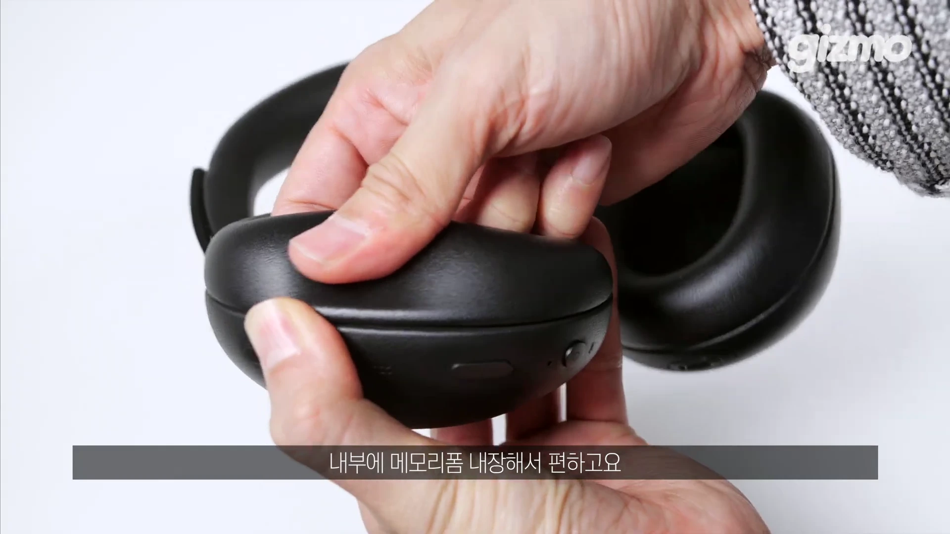 두 손으로 검은색 헤드폰의 가죽 이어패드를 부드럽게 누르고 있는 모습입니다.