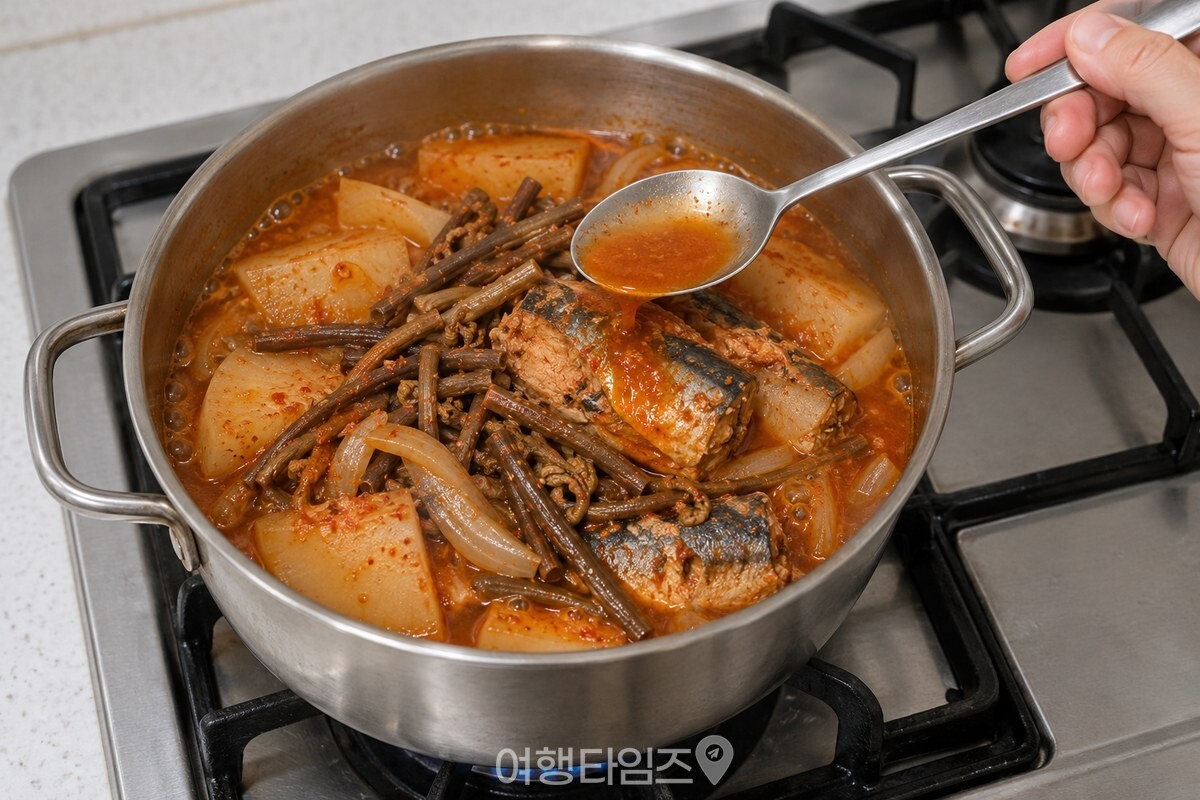 약불에서 조림 국물을 고등어와 고사리 위에 끼얹는 모습 / 기사 이해를 돕기 위한 생성형 이미지