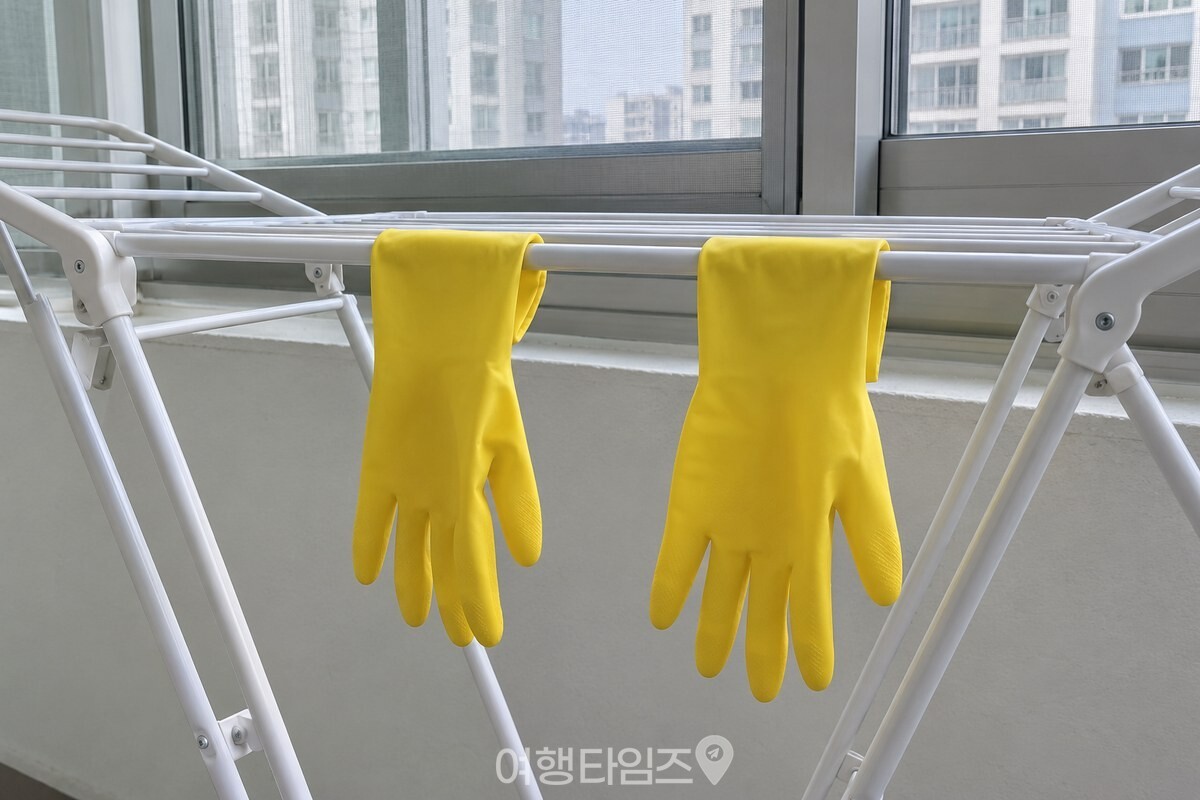 그늘진 베란다 건조대에 뒤집어 걸어 둔 노란 고무장갑 / 기사 이해를 돕기 위한 생성형 이미지