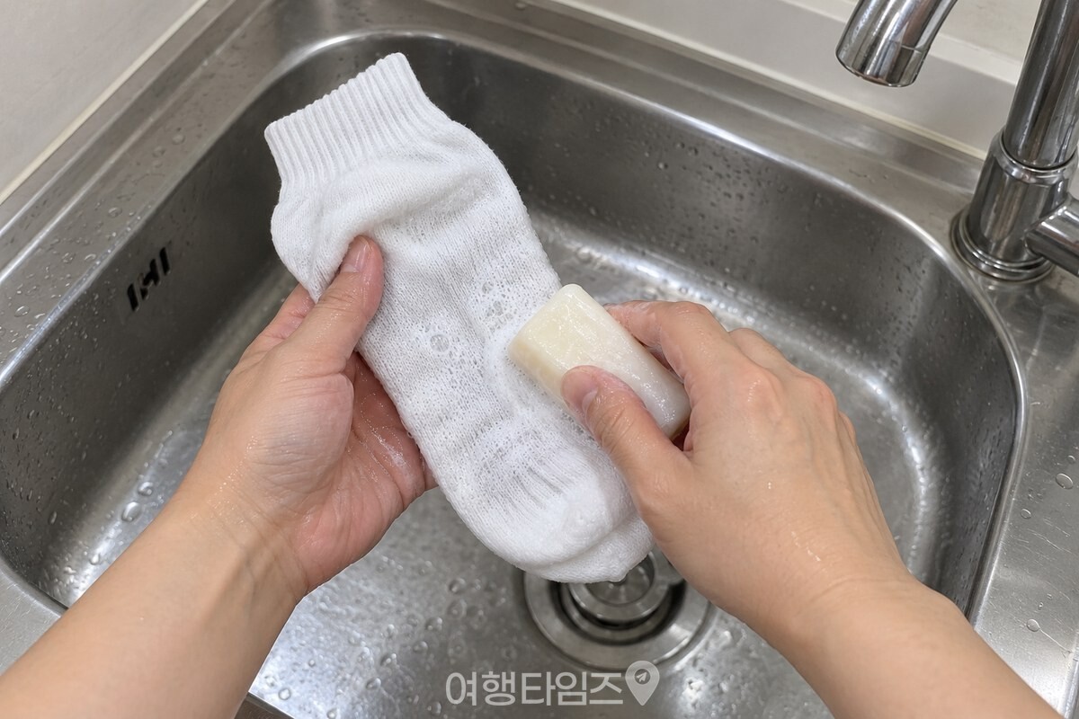 빨랫비누로 흰 양말 발바닥을 애벌빨래하는 모습 / 기사 이해를 돕기 위한 생성형 이미지