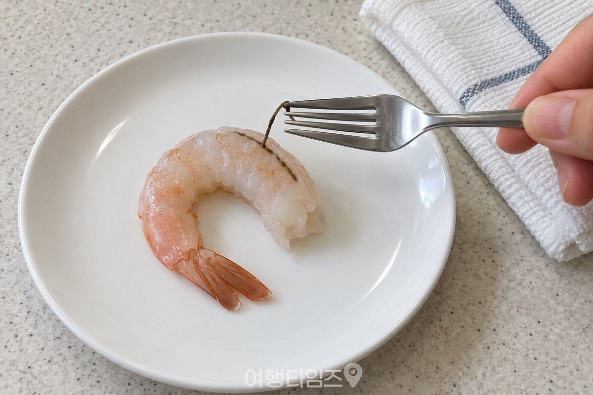껍질을 벗긴 새우의 등 쪽 내장을 포크 끝으로 빼내는 모습 / 기사 이해를 돕기 위한 생성형 이미지