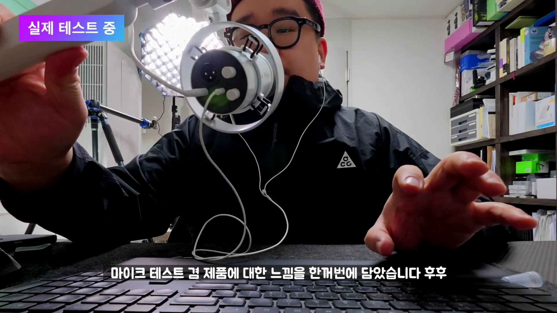 안경을 쓴 남성이 책상 앞에 앉아 다이내믹 마이크의 뒷면 단자를 보여주며 테스트하고 있는 모습