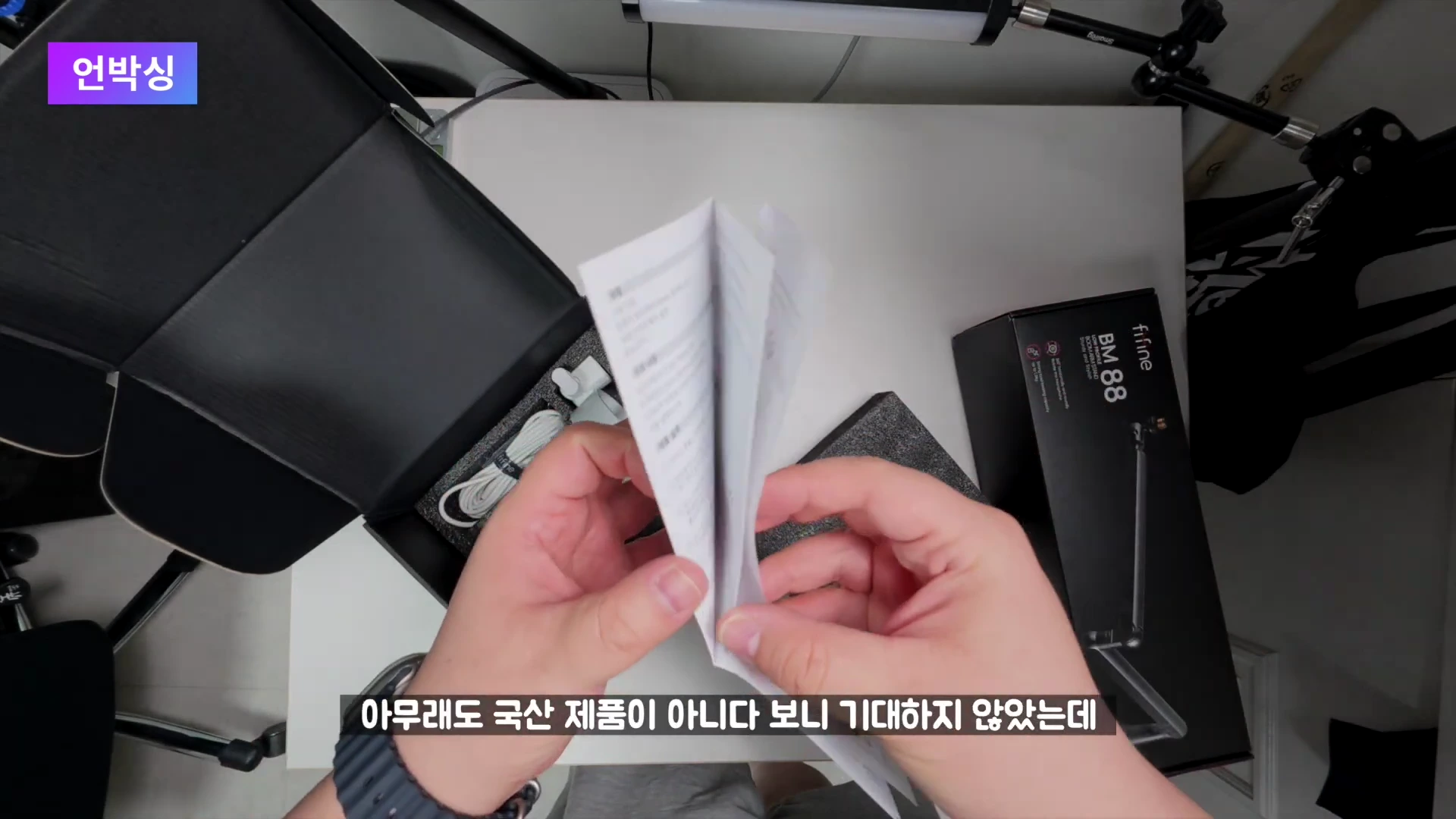 두 손으로 한글 설명서를 펼쳐 들고 있는 모습 위에서 내려다본 촬영 화면