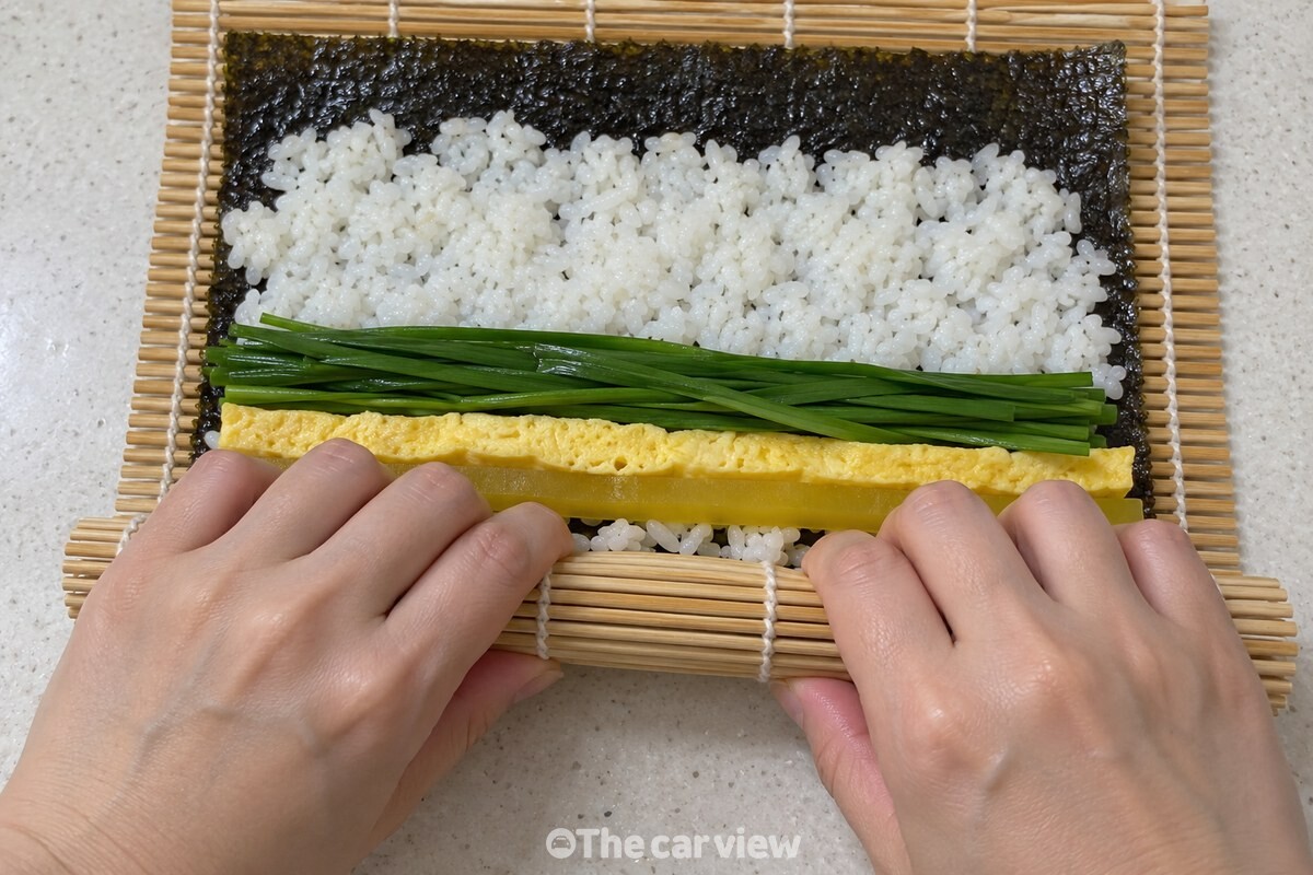 생부추와 달걀을 올려 김밥을 마는 모습 / 기사 이해를 돕기 위한 생성형 이미지