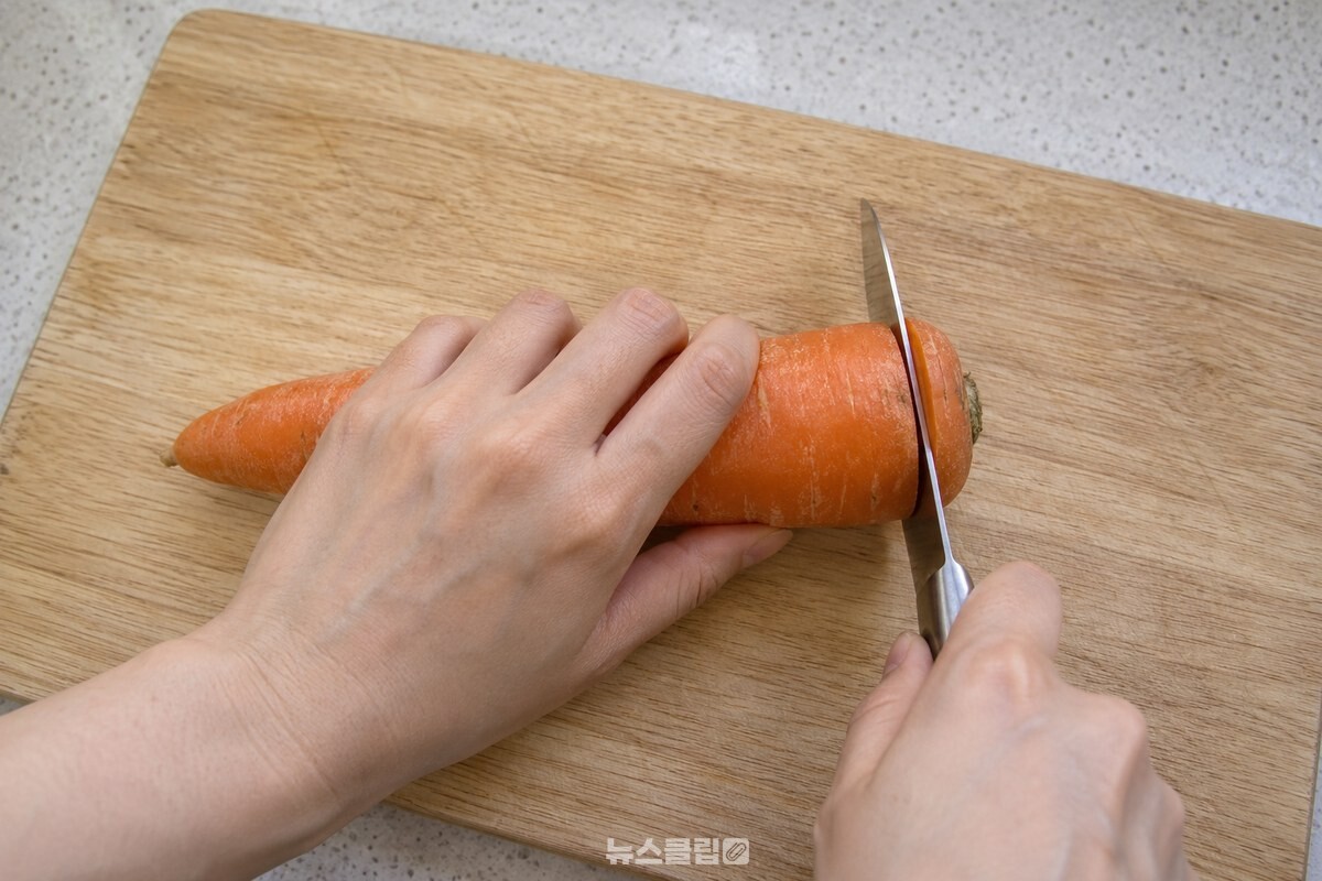 도마 위에서 당근 양 끝을 손질하는 모습 / 기사 이해를 돕기 위한 생성형 이미지