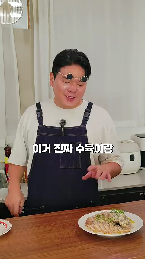 앞치마를 두르고 선글라스를 머리에 얹은 남성이 요리가 완성된 접시를 앞에 두고 설명하고 있다.
