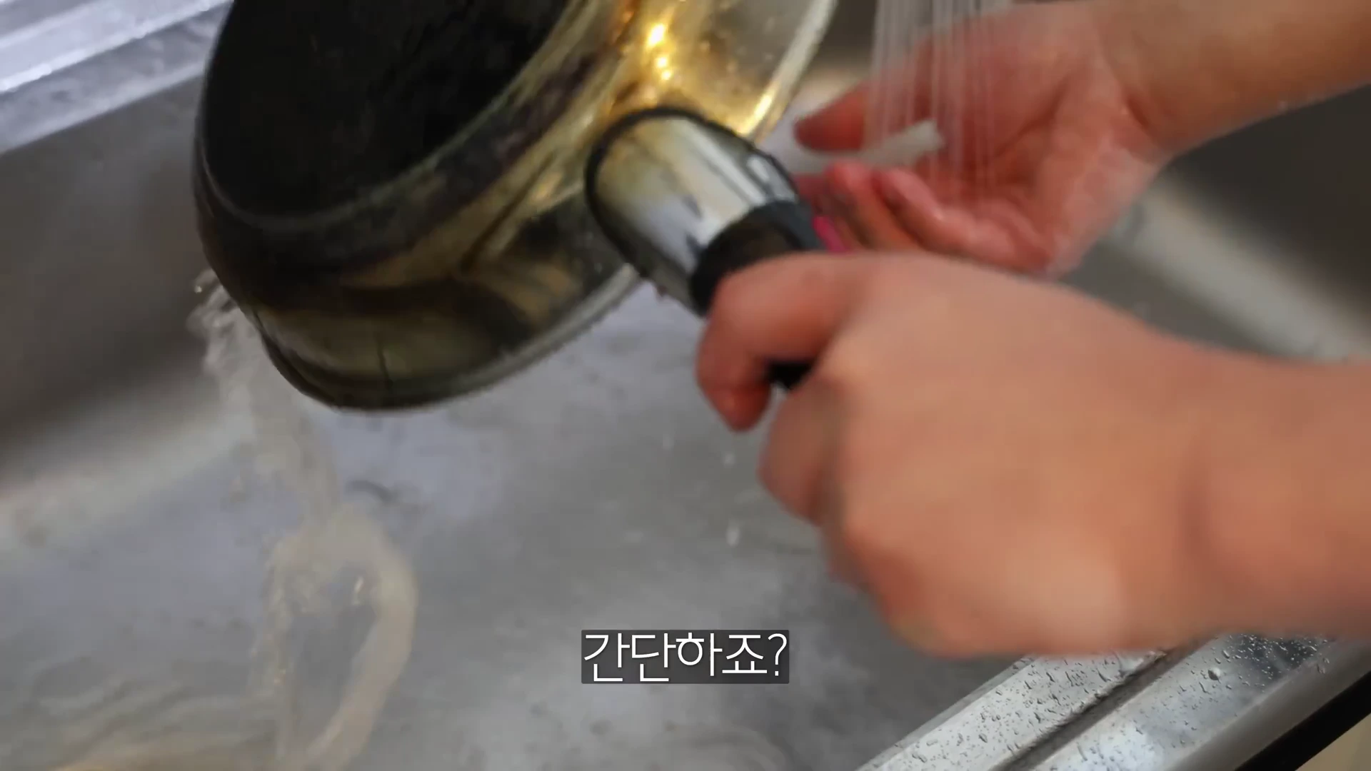 싱크대에서 조리용 프라이팬을 흐르는 물로 씻어내는 사람의 손이 보이며, 화면 하단에는 간단하죠? 라는 한국어 자막이 적혀 있습니다.