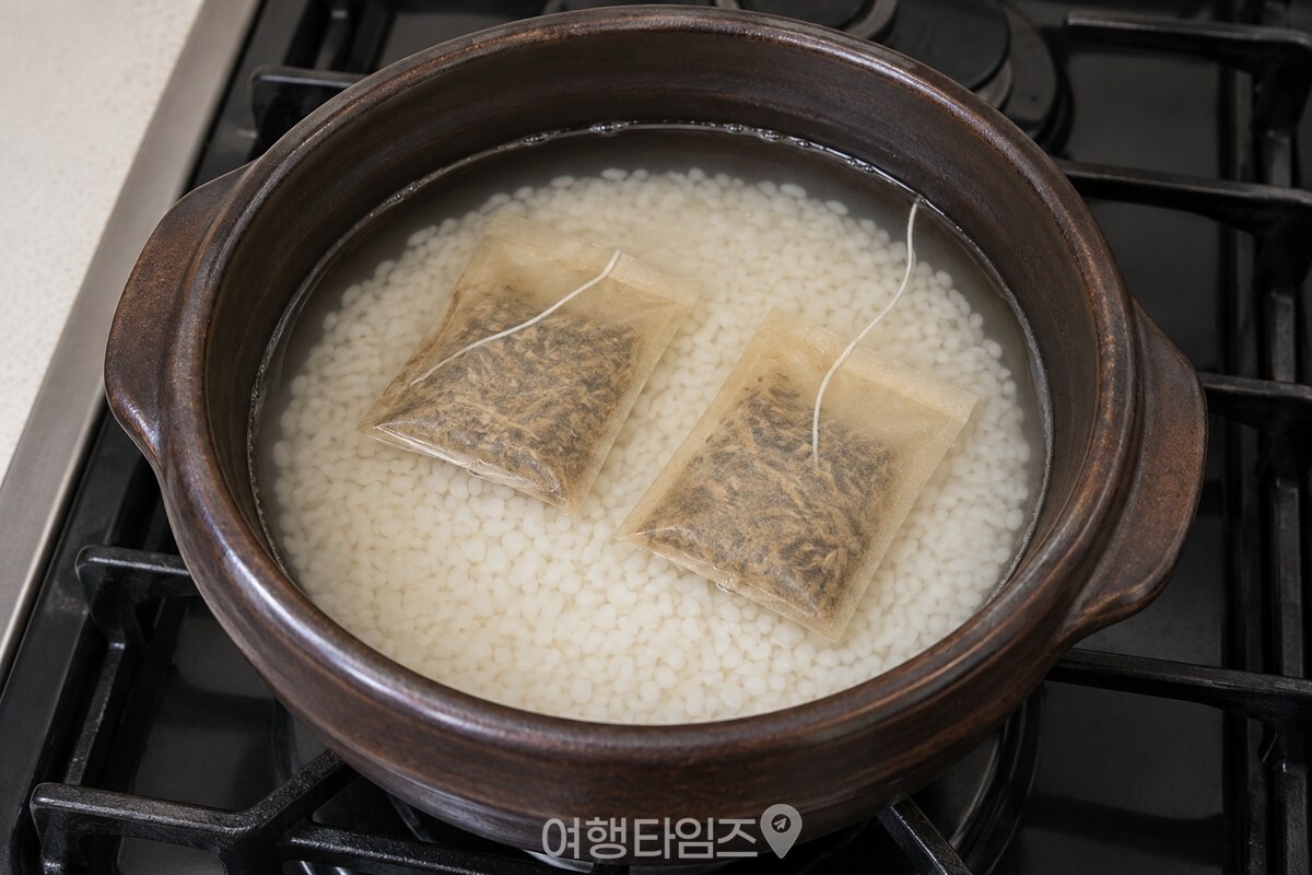 불린 쌀과 물 위에 우엉차 티백 두 개를 올린 솥 / 기사 이해를 돕기 위한 생성형 이미지