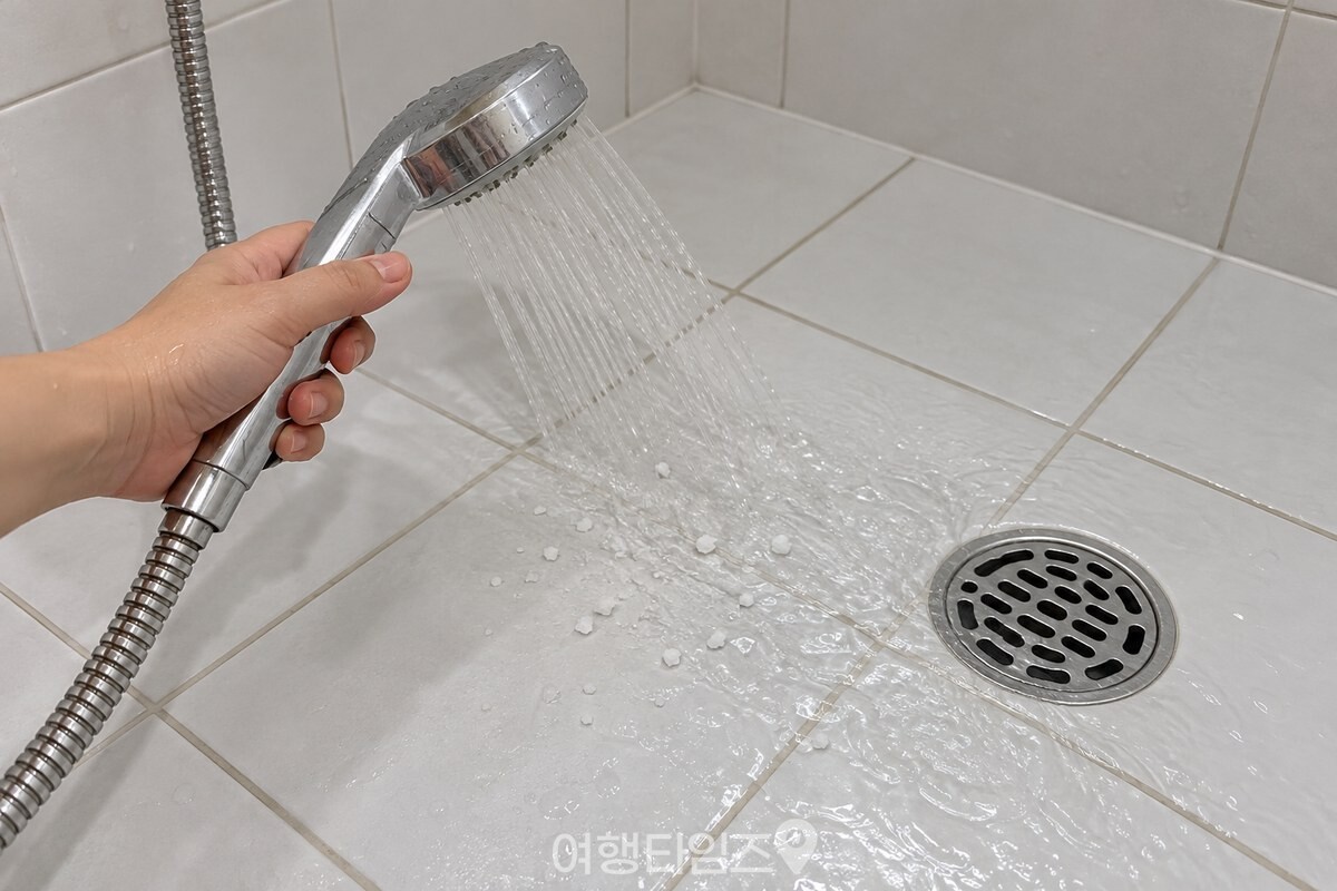 샤워기 물로 소금을 배수구 쪽으로 헹구는 모습 / 기사 이해를 돕기 위한 생성형 이미지