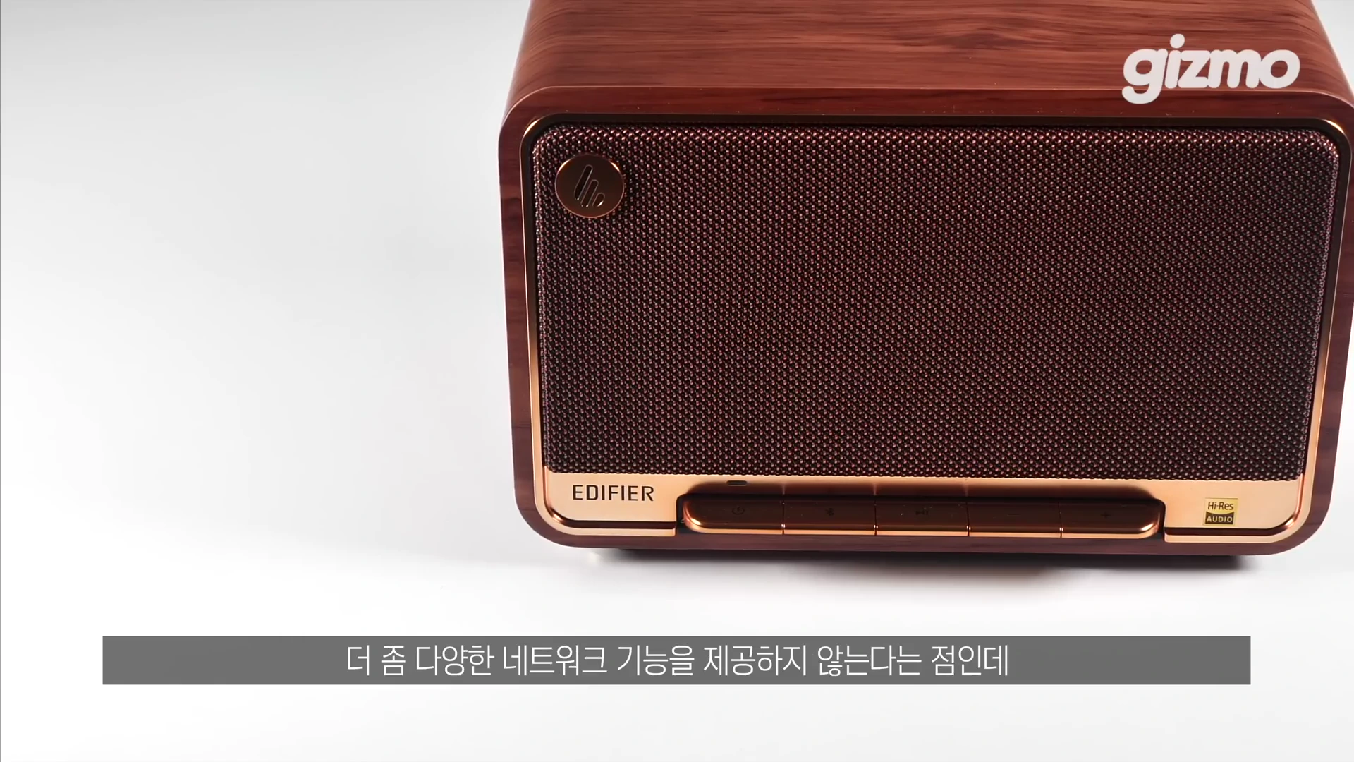 나무 무늬 질감의 본체와 금색 테두리, 전면 그릴이 특징인 에디파이어 스피커 제품이 흰색 배경에 놓여 있고 하단에는 자막이 떠 있다.