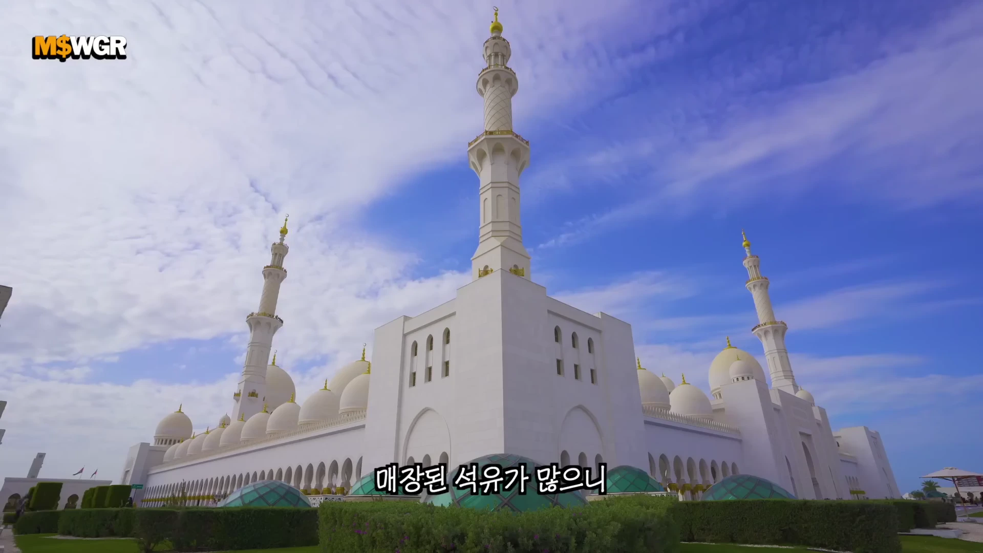 푸른 하늘을 배경으로 하얀색의 웅장한 사원 건물이 보이며, 건물에는 여러 개의 돔과 높은 첨탑이 솟아 있다.