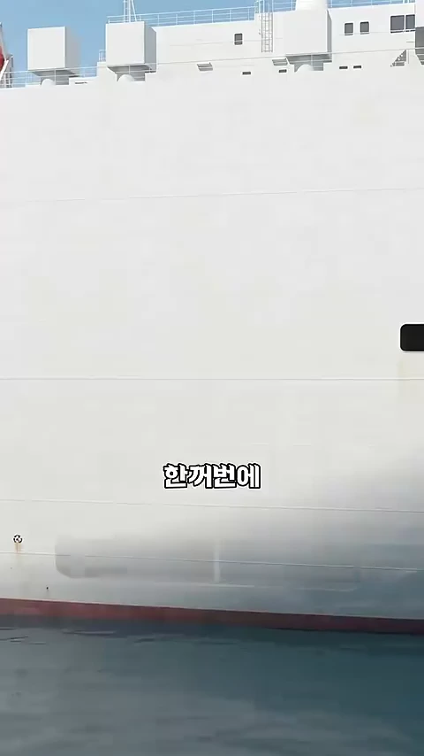 바다 위에 떠 있는 거대한 자동차 운반선의 하얀색 선체 옆면 모습