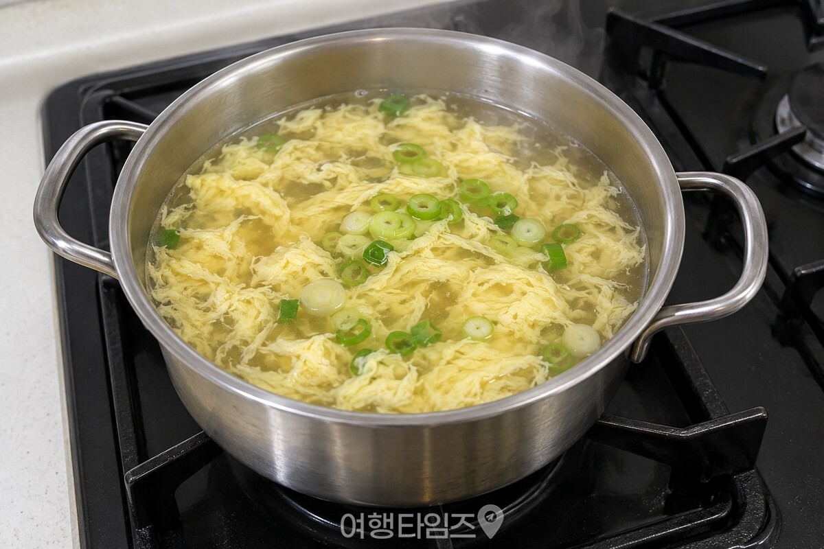 익은 달걀 가닥 위에 썬 대파를 올린 계란국 냄비 / 기사 이해를 돕기 위한 생성형 이미지