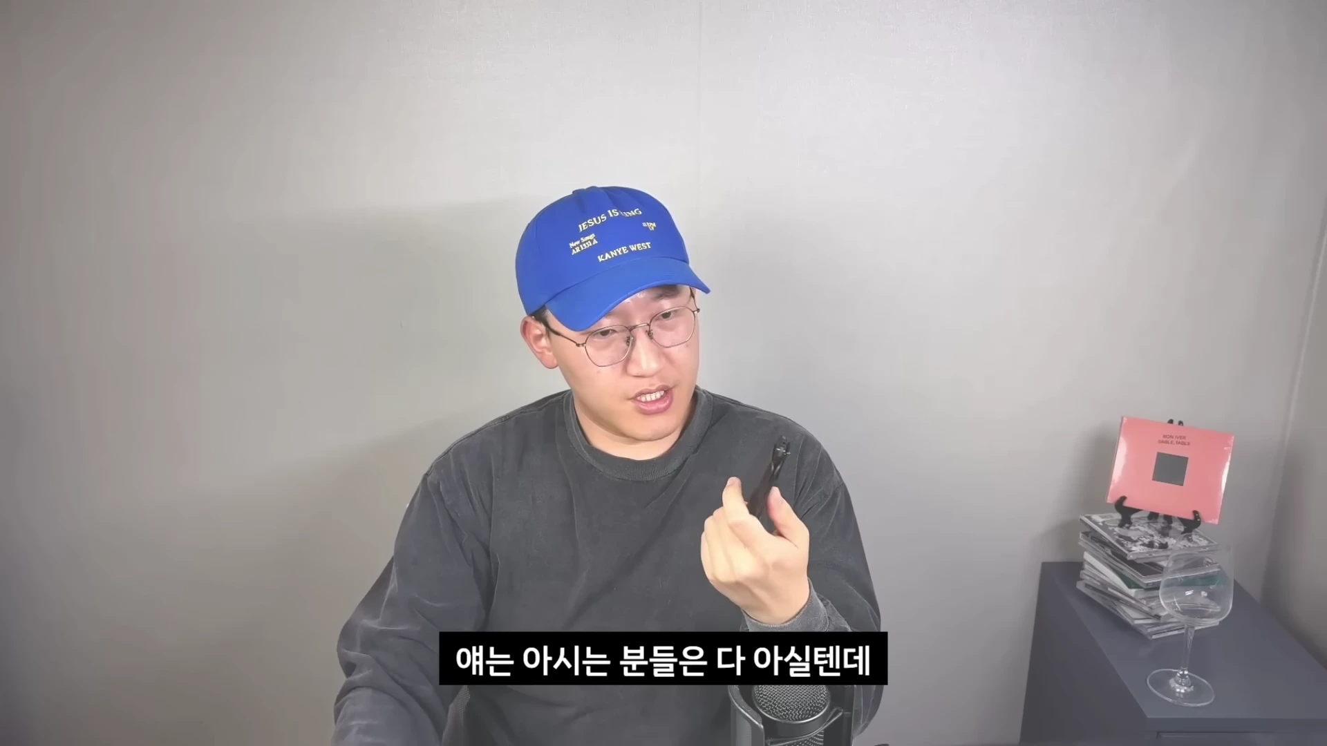 파란색 모자를 쓰고 안경을 쓴 남성이 영상 촬영을 위해 사용하는 소형 음성 녹음 장비를 손에 들고 설명하고 있다.