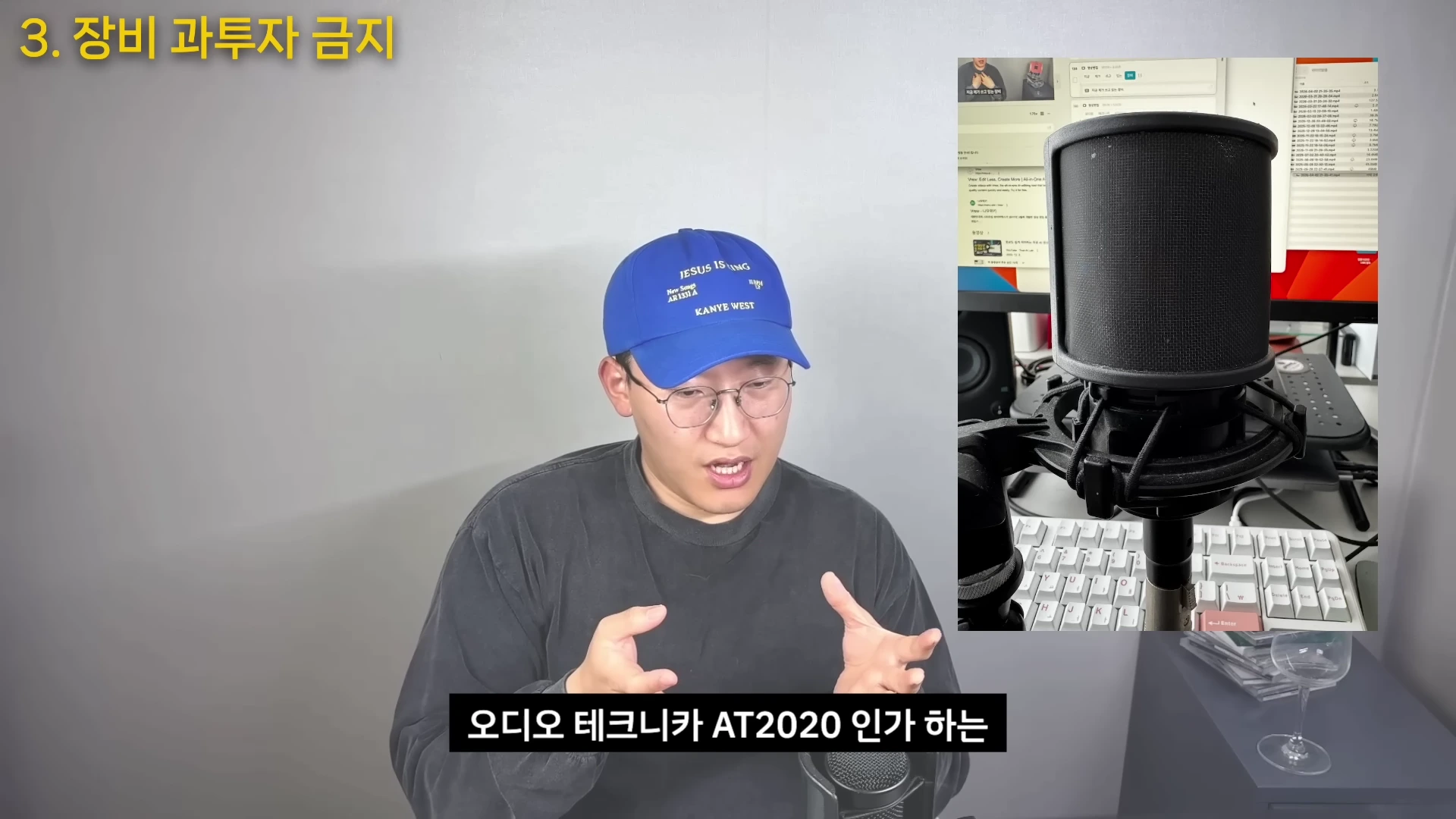 파란색 야구 모자를 쓴 안경 낀 남성이 카메라를 보며 이야기하고 있고, 화면 오른쪽에는 마이크와 컴퓨터 키보드가 클로즈업된 영상이 합성되어 있음.