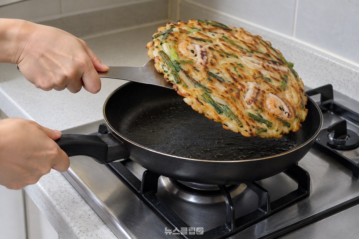 파전 밑을 넓은 뒤집개로 받쳐 뒤집는 모습 / 기사 이해를 돕기 위한 생성형 이미지