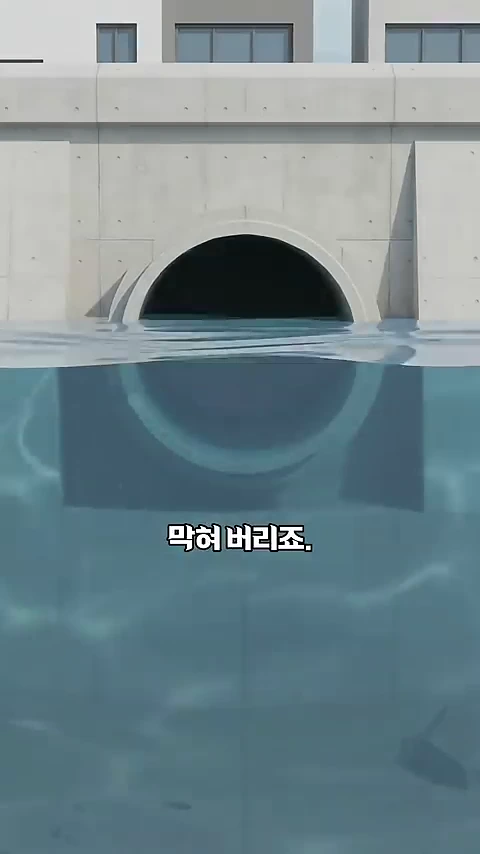 콘크리트로 만들어진 하천 배수관 입구가 물속에 반쯤 잠겨 있으며 하단 중앙에 '막혀 버리죠.'라는 한국어 자막이 표시된 그래픽 이미지