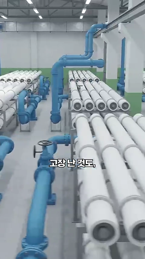 해수담수화 공장 내부에 역삼투막 필터가 포함된 흰색 원통형 장치들이 여러 줄로 배치되어 있고, 파란색 연결 배관이 복잡하게 얽혀 있는 모습.