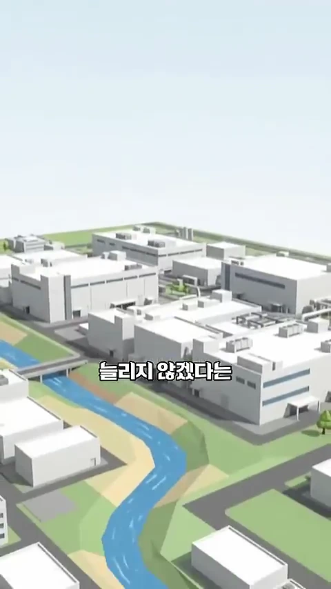 3D 그래픽으로 구현된 반도체 공장 단지와 그 옆으로 흐르는 푸른 강물이 묘사된 이미지.