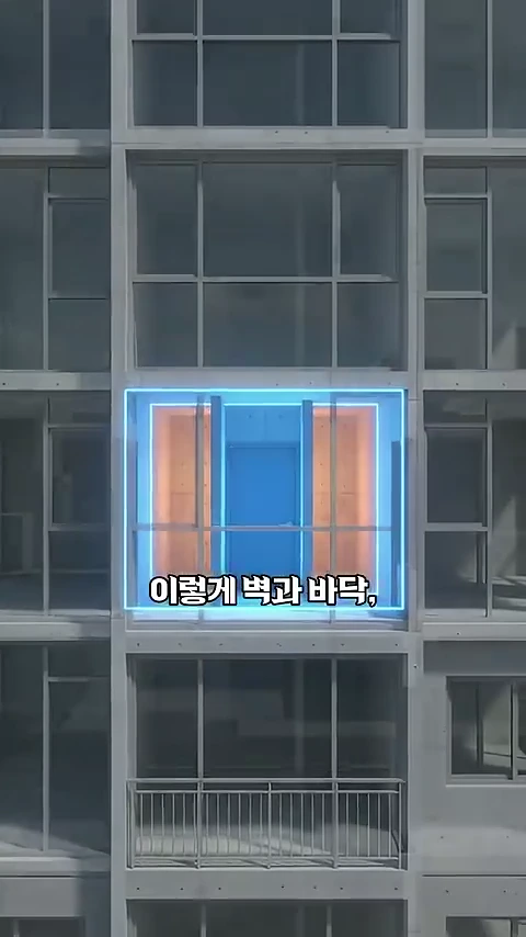 현대식 아파트 건물의 외벽을 보여주는 영상 그래픽에서 특정 세대 공간이 푸른색 조명으로 강조되고 그 위에 '이렇게 벽과 바닥'이라는 한글 자막이 떠 있습니다.