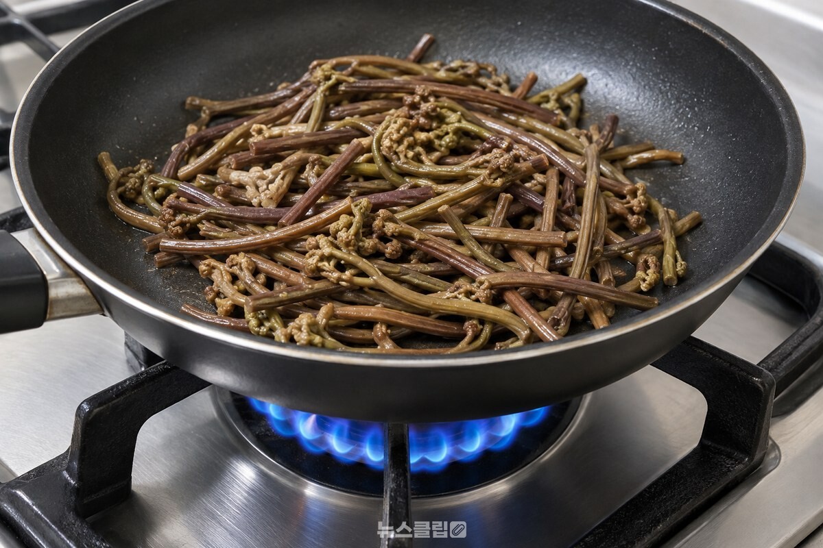 센 불의 팬에서 마르기 시작한 삶은 고사리 줄기 / 기사 이해를 돕기 위한 생성형 이미지
